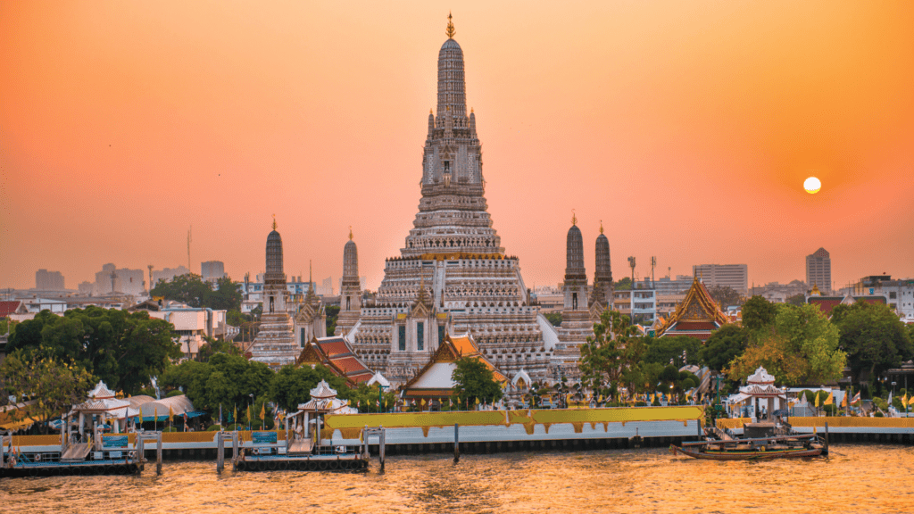 Vista de Bangkok al atardecer con colores cálidos iluminando la ciudad y su arquitectura.
