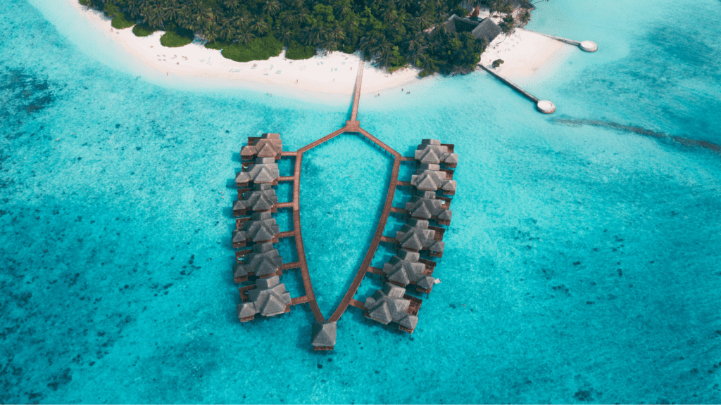 Cabañas sobre el agua cristalina en las Maldivas, rodeadas de un paisaje tropical y cielo despejado.