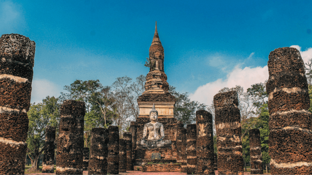 Paseo de piedra en Sukhothai, Tailandia, que conduce a un monumento con un Buda en el centro.