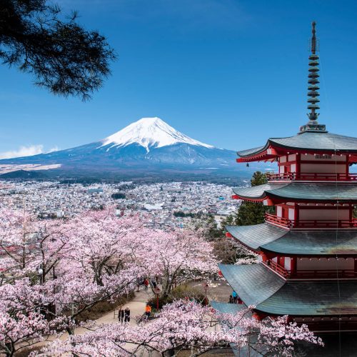 Vista panorámica del Monte Fuji al amanecer, rodeado de naturaleza y reflejado en el lago Kawaguchi, un destino emblemático para viajes a Japón