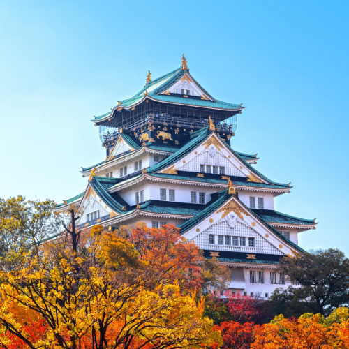 Templo en Osaka rodeado de árboles con tonos naranjas, una escena típica de los viajes a Japón